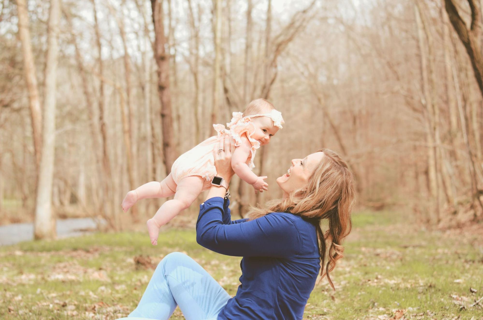 A mother with her baby girl sits in a park.