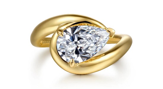 a yellow gold engagement ring with a unique curved silhouette and pear shape diamond