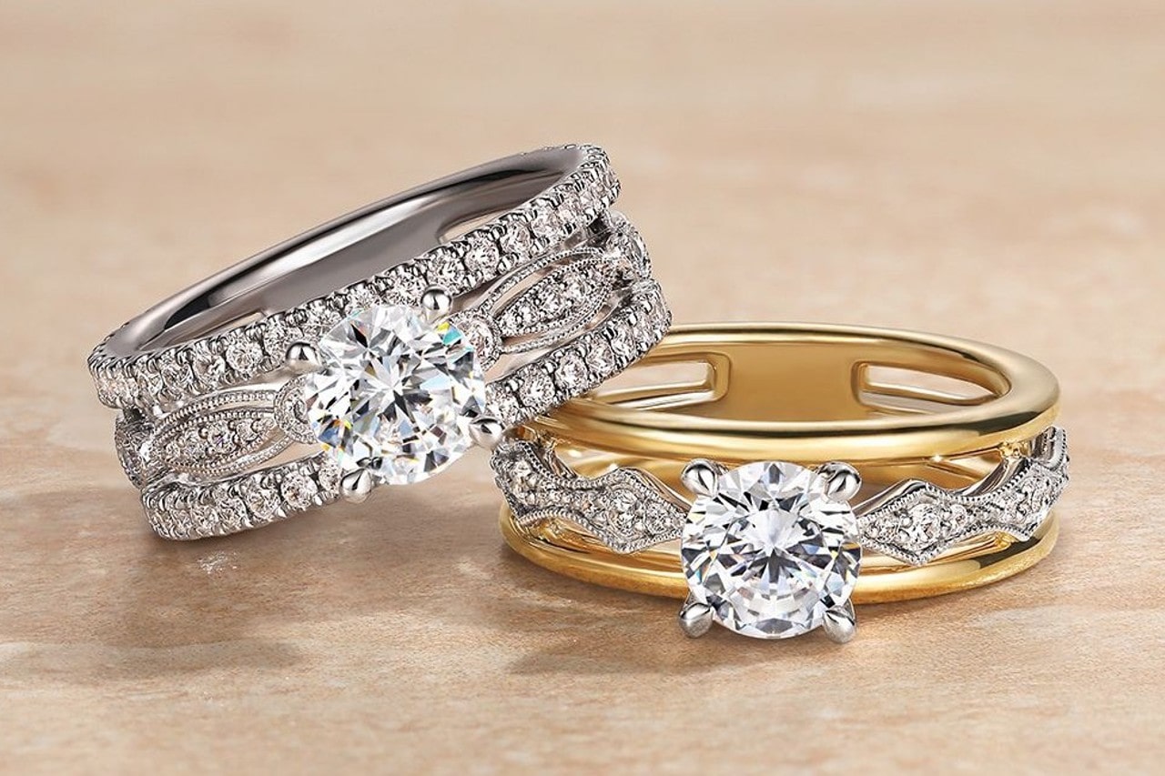 two diamond engagement rings with wide bands and intricate details