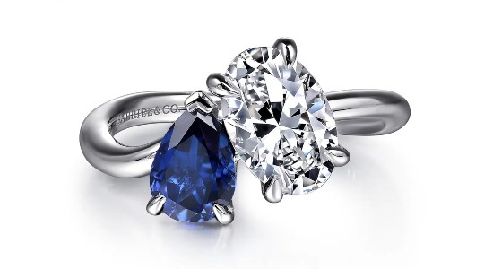 a white gold toi et moi engagement ring with a pear shaped sapphire and oval diamond