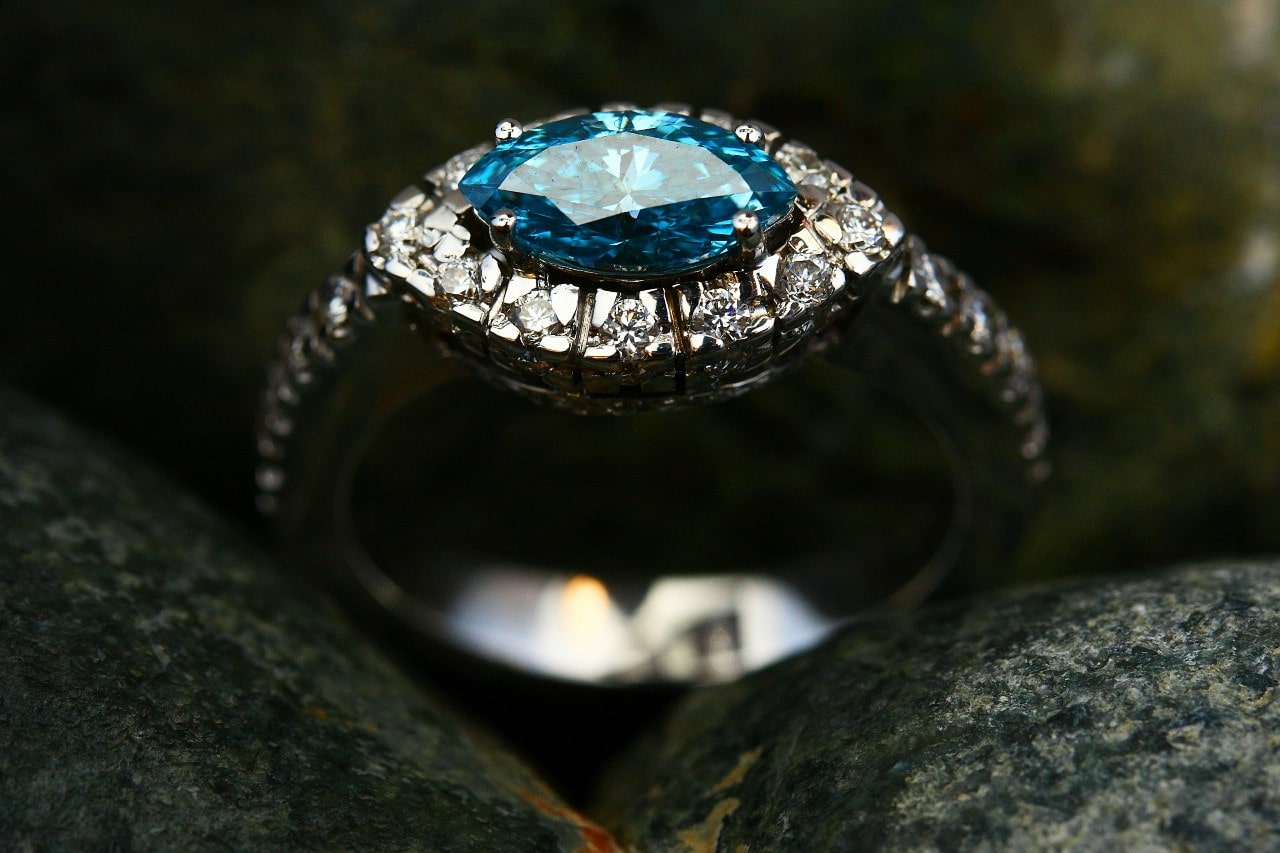 A close up of a topaz engagement ring on some rocks.