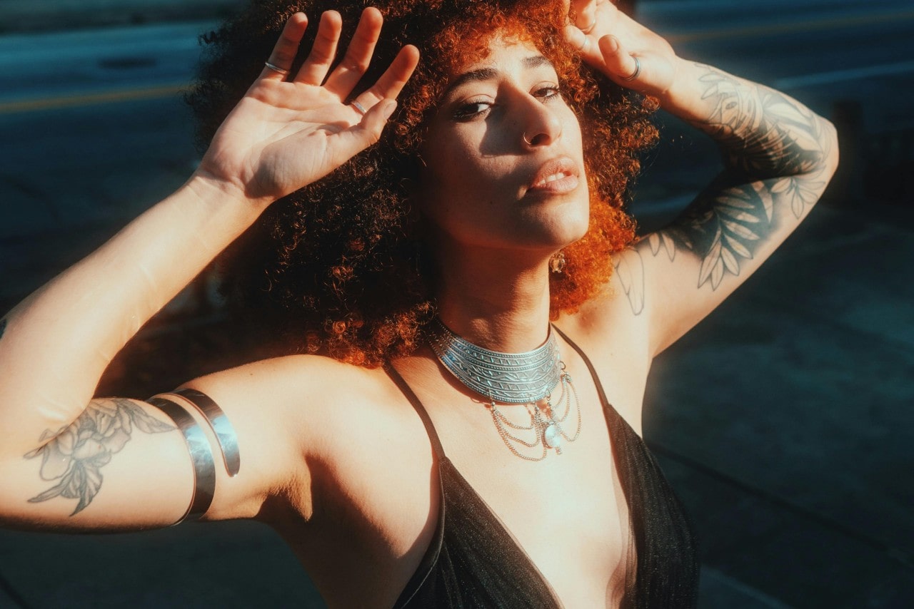 a woman standing in the sun wearing bold silver jewelry