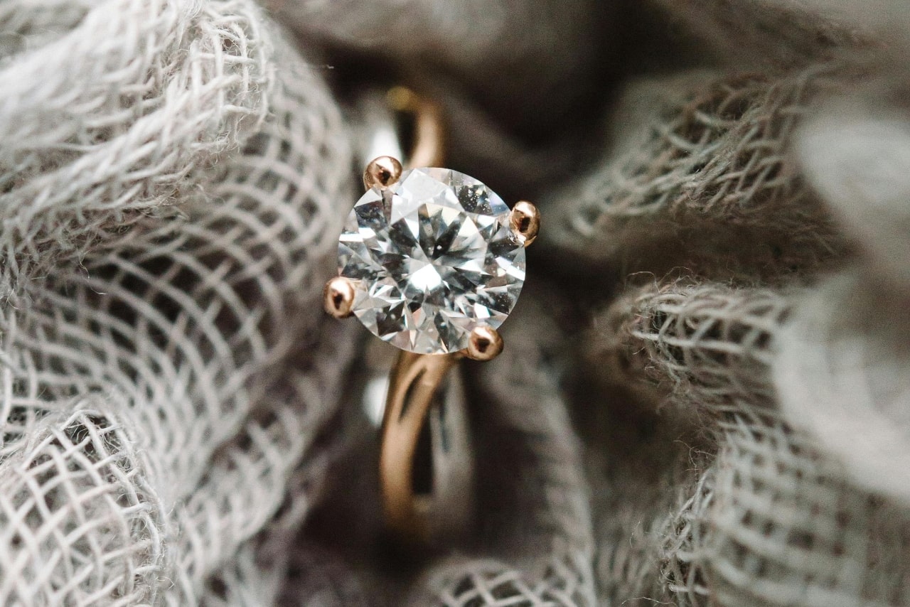 a yellow gold solitaire diamond engagement ring surrounded by burlap