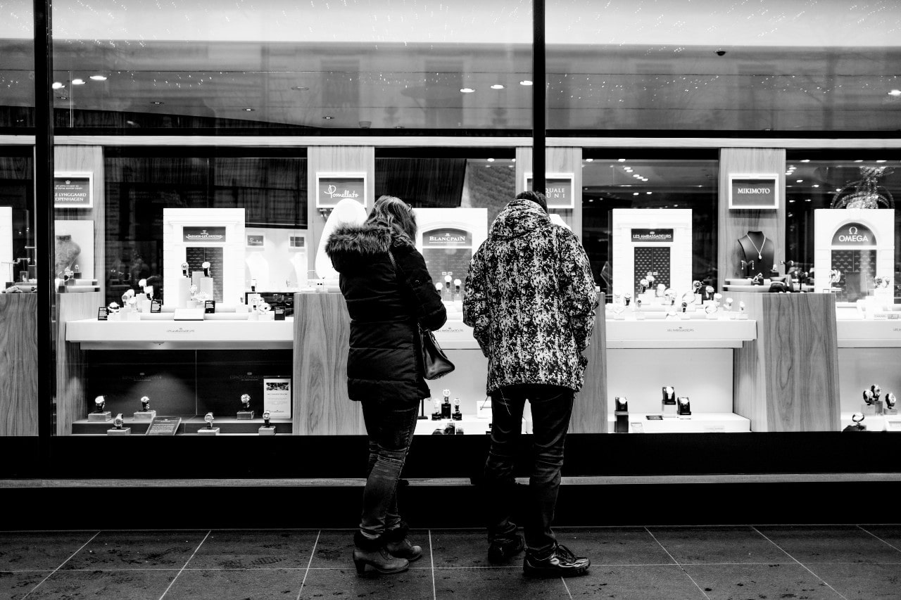 A black and white image of a couple window shopping outside of a luxury jewelry store.