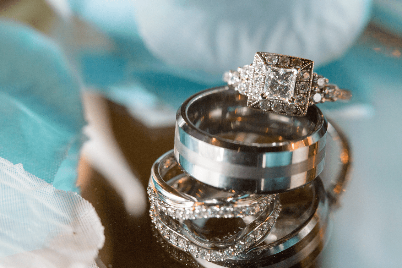 A close-up of a stack of a white gold diamond wedding rings on a reflective surface.