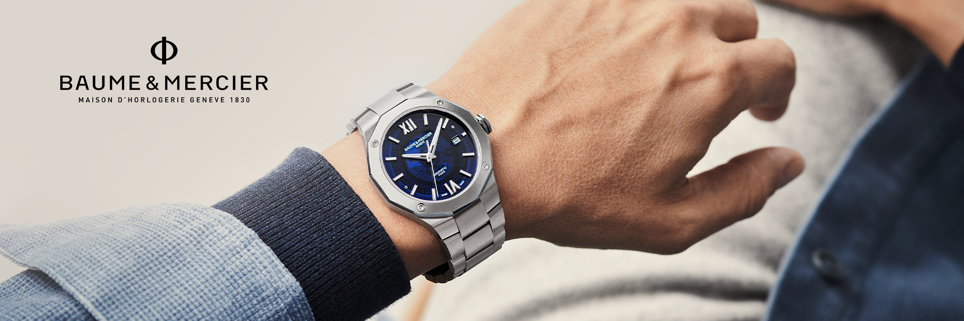 A hand with a watch on the wrist with text Baume and Mercier.