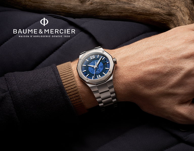 A hand with a watch on the wrist with text Baume and Mercier.
