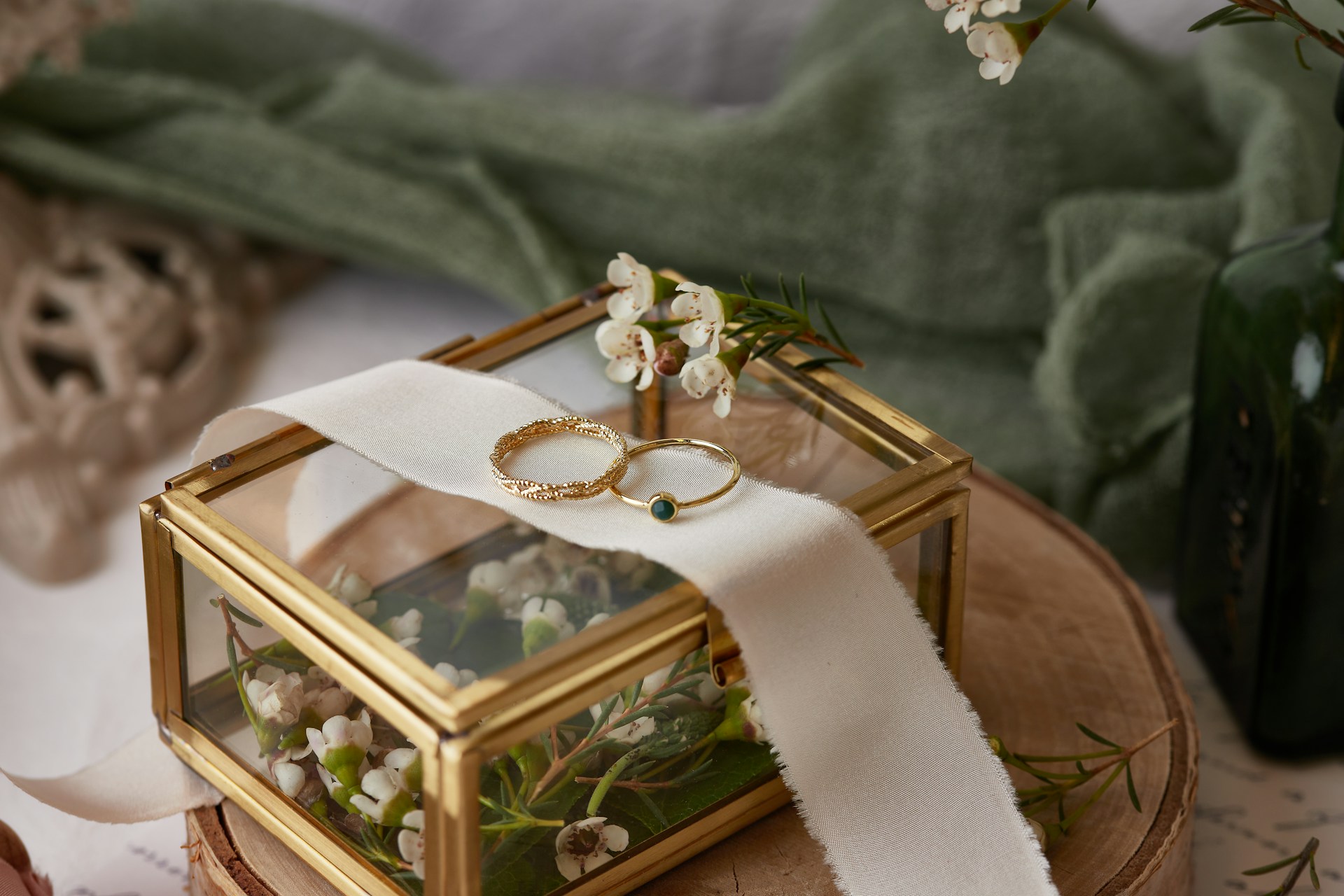 A close up of two thin yellow gold wedding bands on top of a glass box with flowers inside A close up of two thin yellow gold wedding bands on top of a glass box with flowers inside