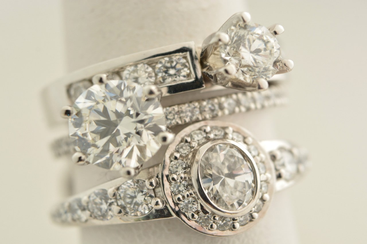 A stack of three elegant diamond rings with various settings and cuts, showcasing sparkling clarity.