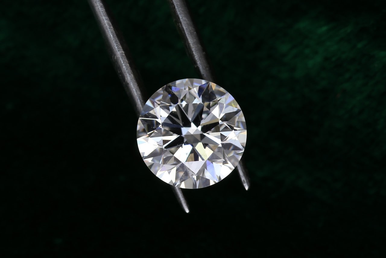 a close up of a round brilliant diamond against an emerald green background a close up of a round brilliant diamond against an emerald green background
