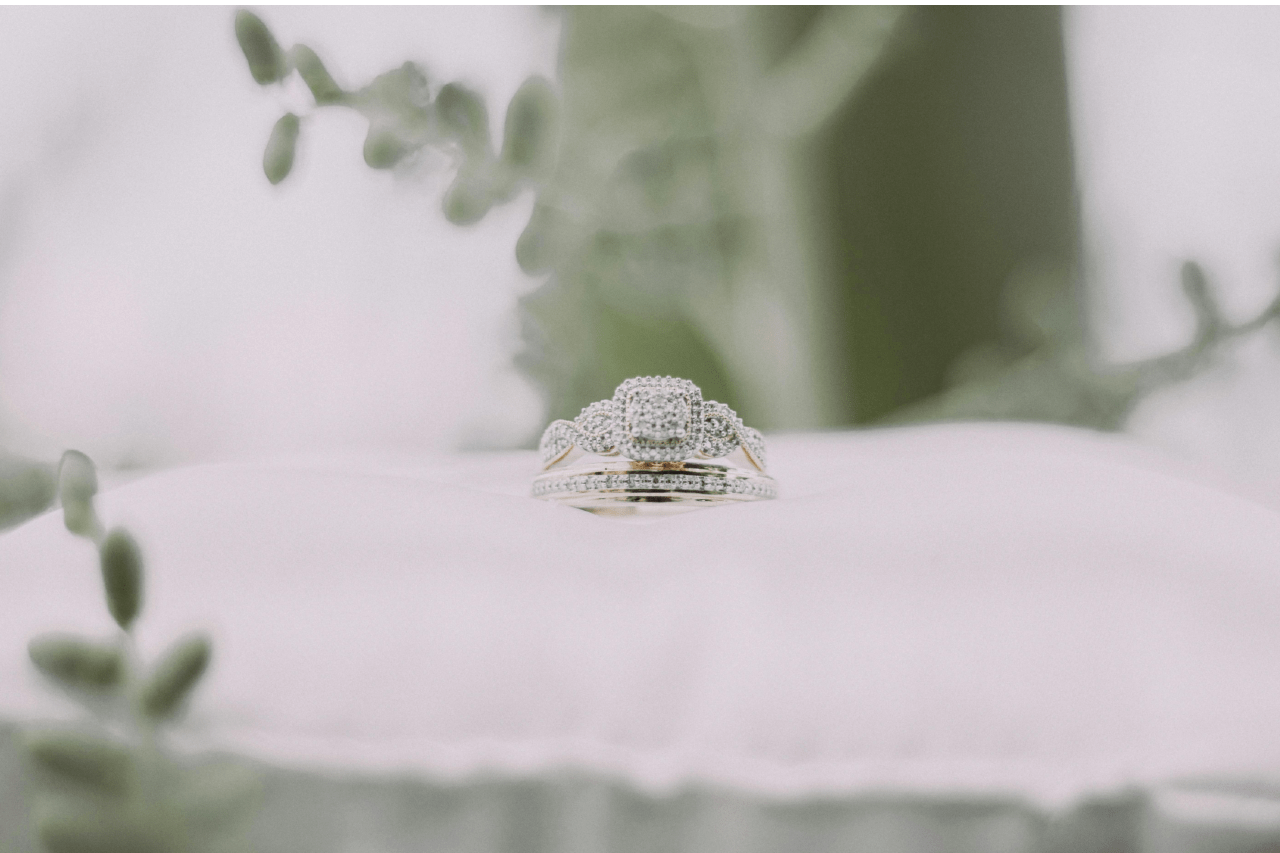 A white gold diamond engagement ring and wedding band sitting on a white pillow. A white gold diamond engagement ring and wedding band sitting on a white pillow.