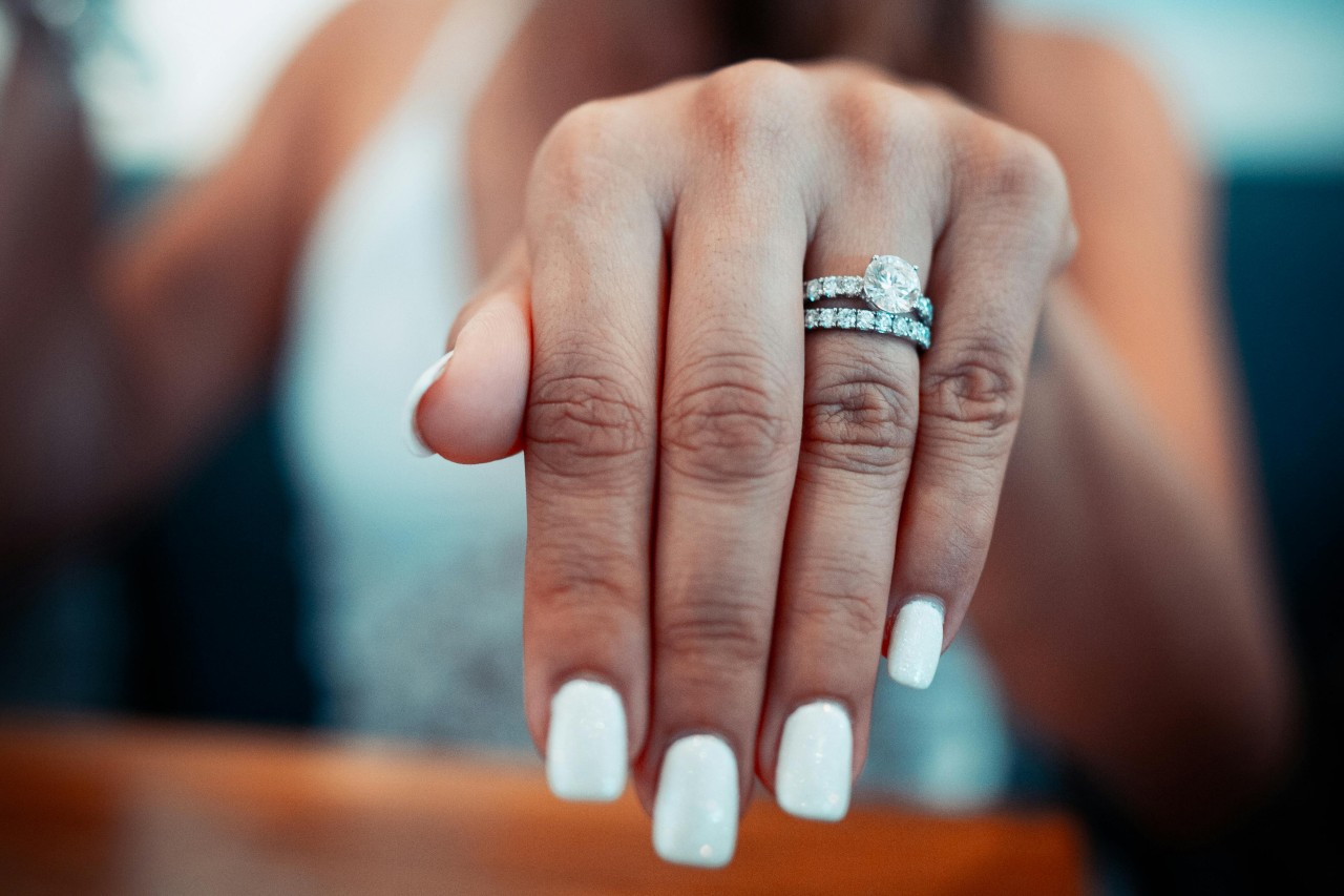 A woman’s outstretched hand, adorned with a diamond engagement ring and wedding band. A woman’s outstretched hand, adorned with a diamond engagement ring and wedding band.