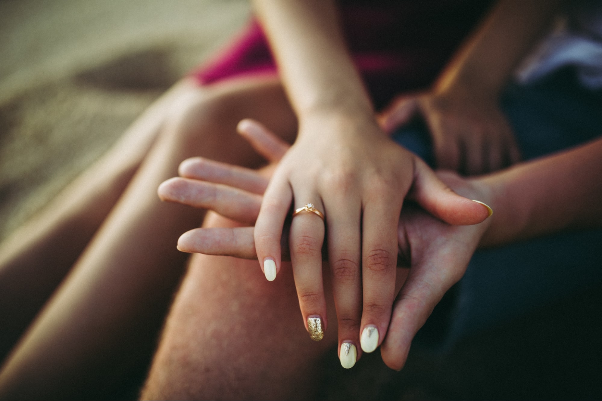 a woman holding a man’s hand and wearing a gold engagement ring