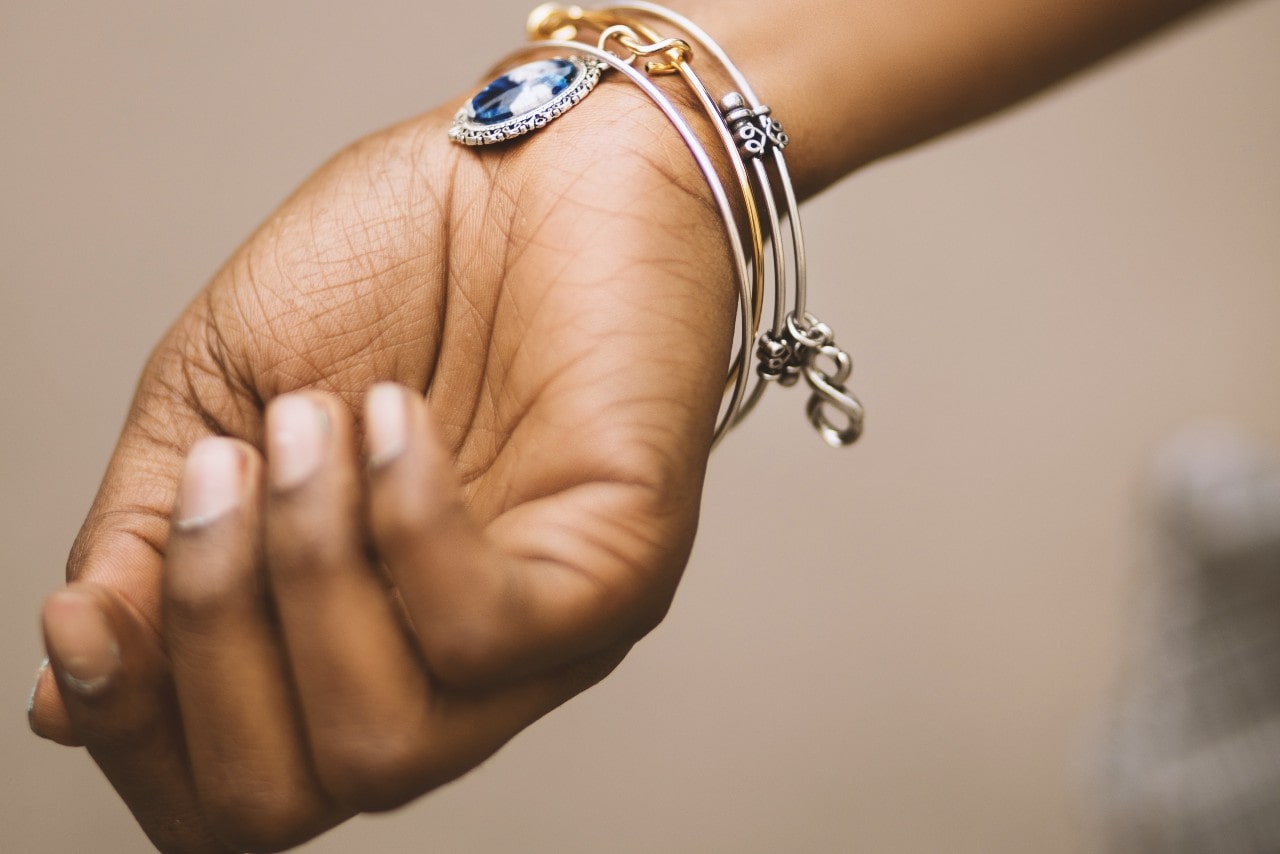 A woman wears a vintage-inspired aquamarine charm bangle on her wrist as she holds her hand out to show it off to her friends