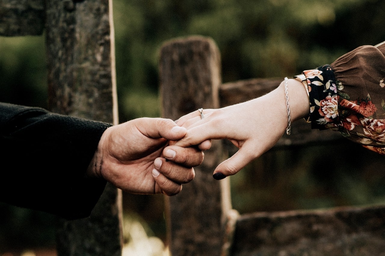 A man and woman hold hands to show off her engagement ring