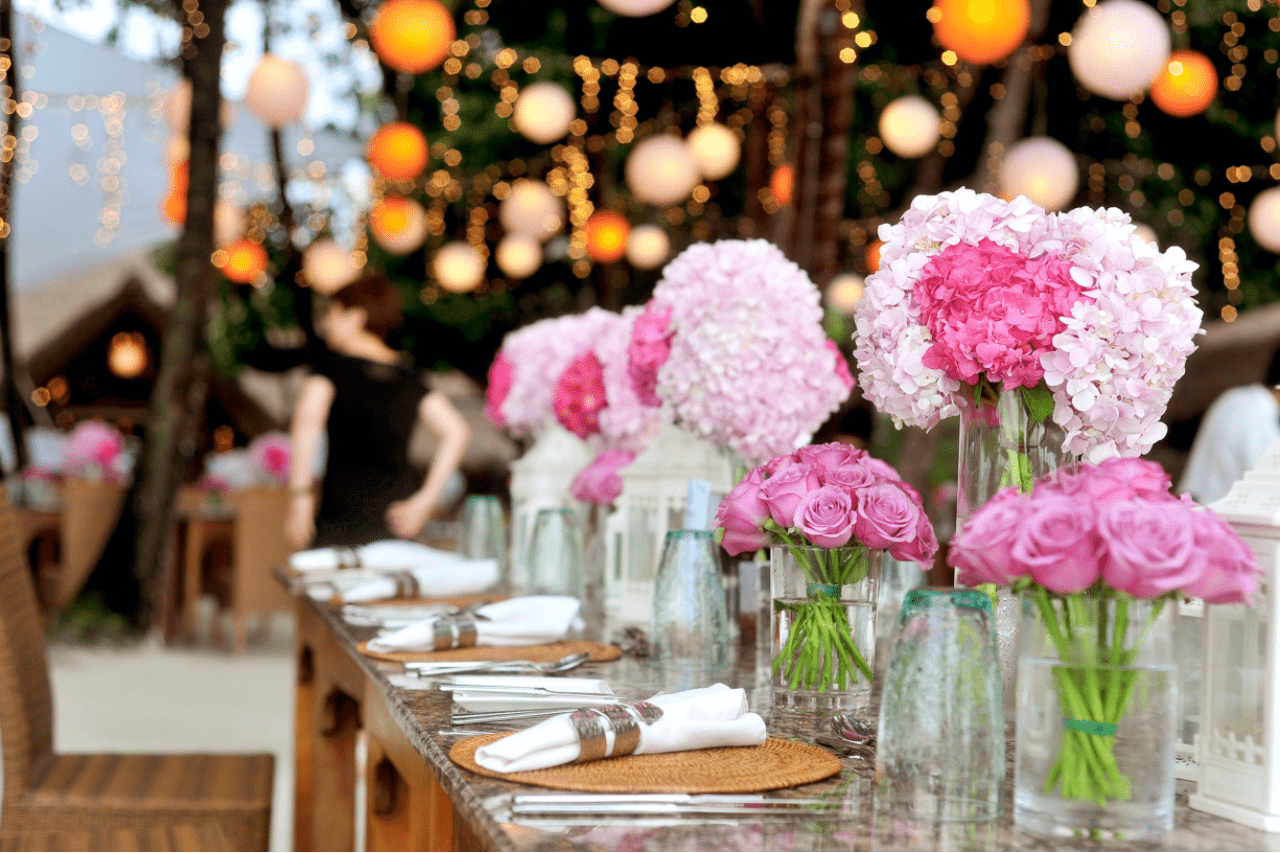 A table setting at a wedding reception features pink flower centerpieces