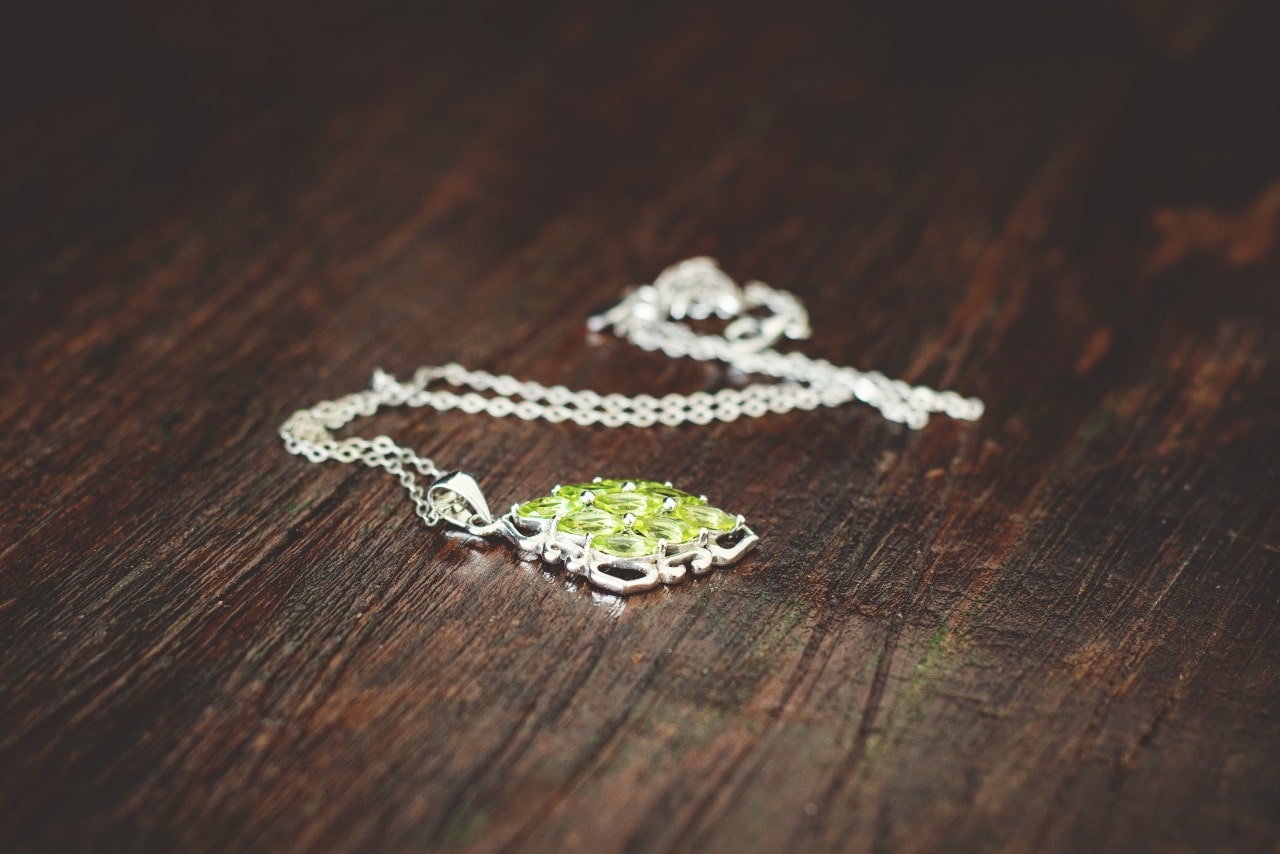 Peridot and white gold necklace on a wooden table