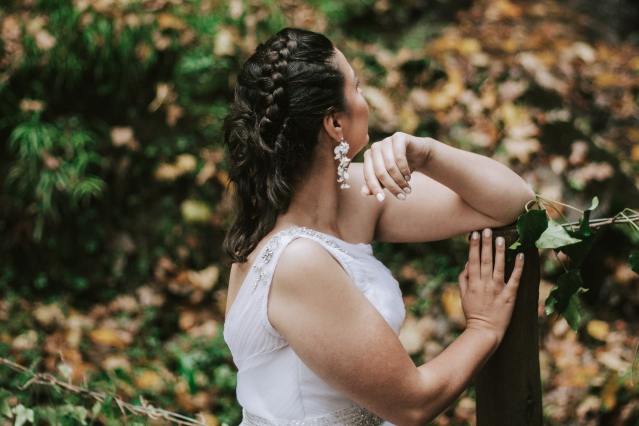 a bride facing away from the camera in the woods in the fall