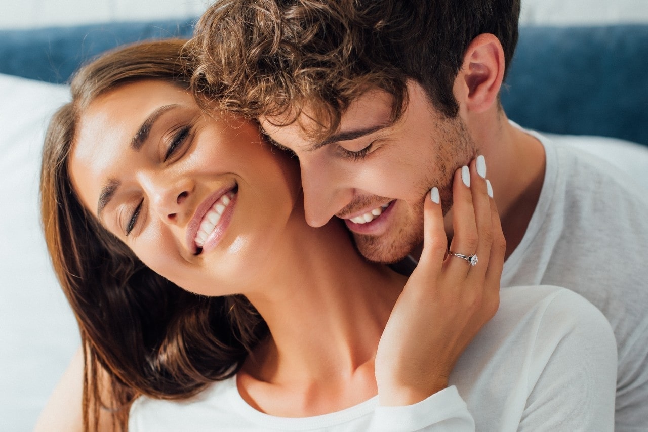 lady wearing a custom-designed engagement ring and embracing her fiancee