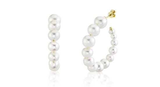 a pair of pearl huggie earrings featuring pearls descending in size to create a crescent shape