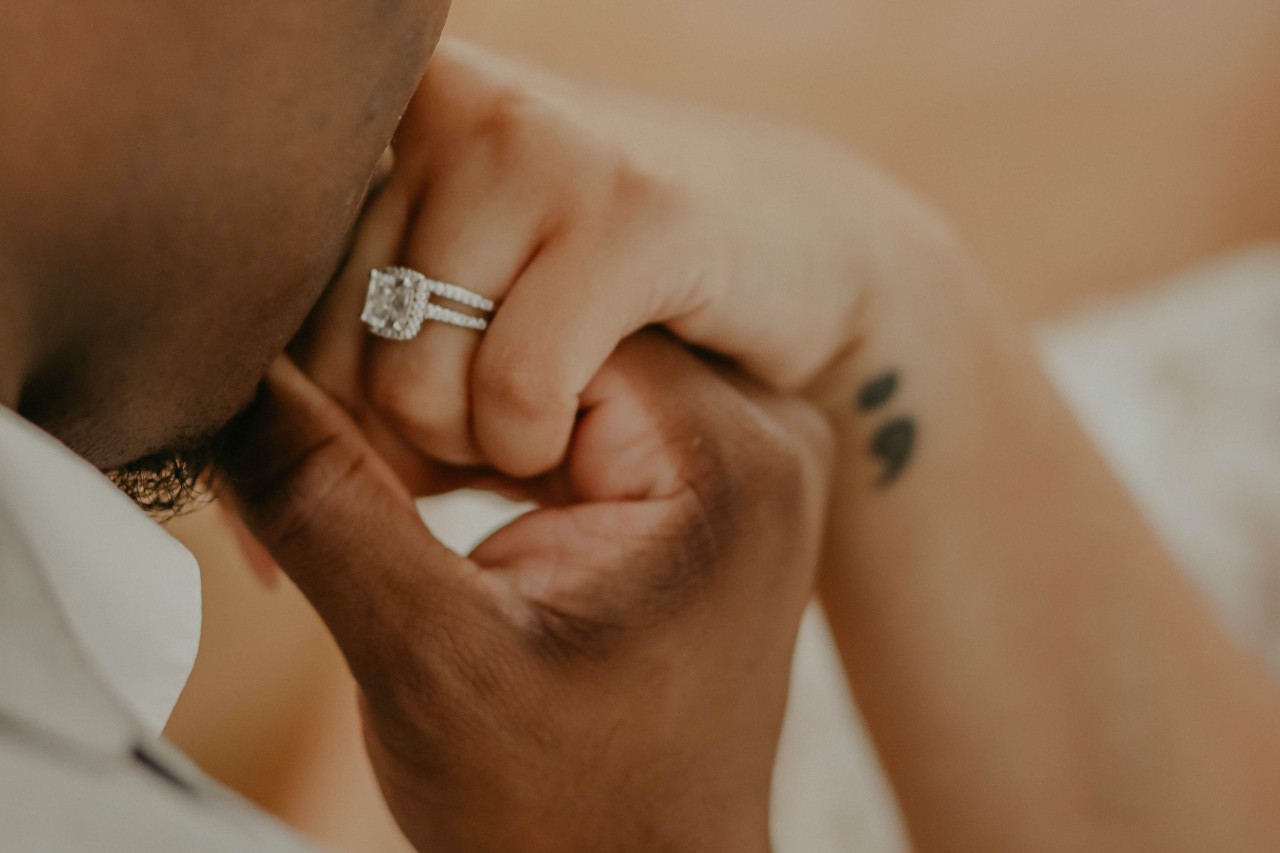 a man kissing a woman’s hand wearing a diamond engagement ring
